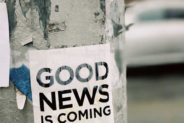 a poster on a tree saying 'good news is coming'.