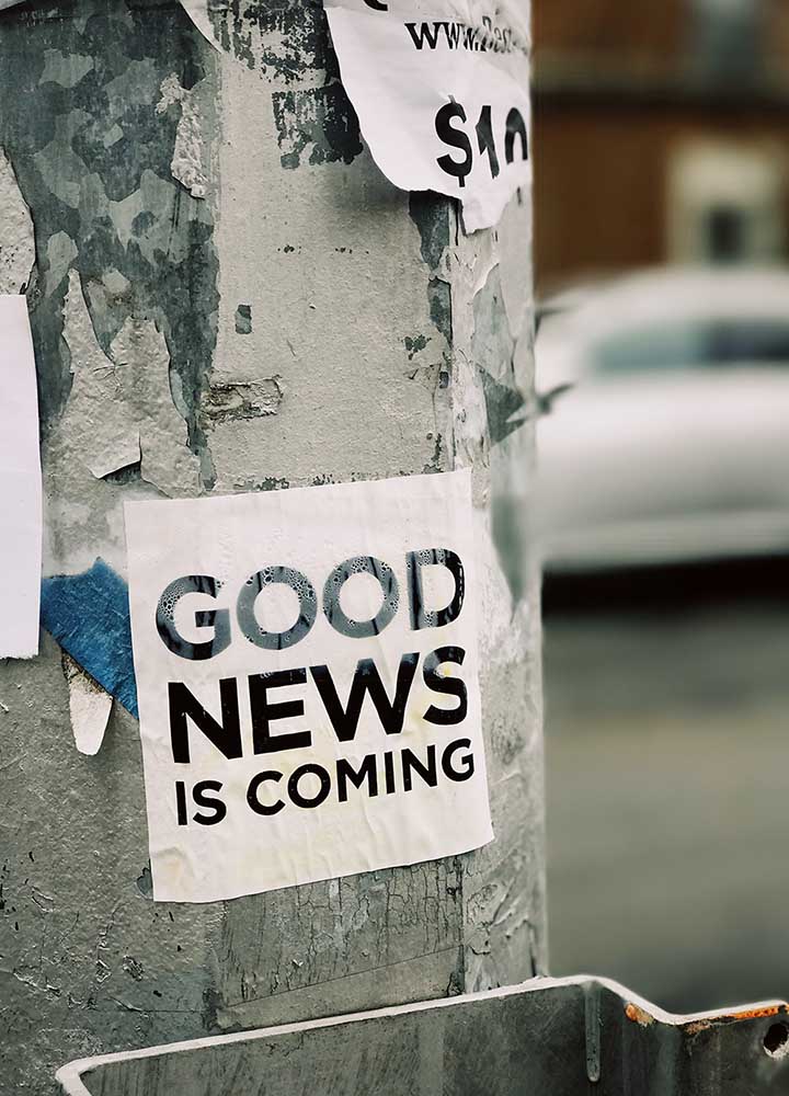 a poster on a tree saying 'good news is coming'.