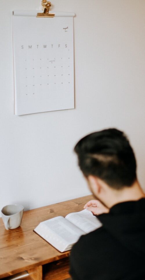 Man reading Bible with Calendar on the wall